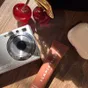 A flat lay from my desk: a vintage camera, a cherry ornament and a lip balm in afternoon sun