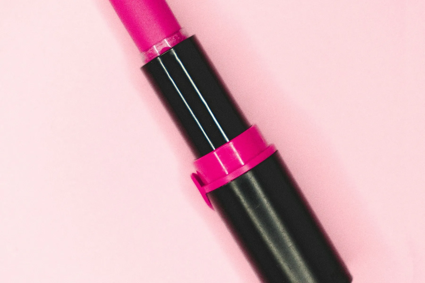 A pink lipstick lying on a soft pink background